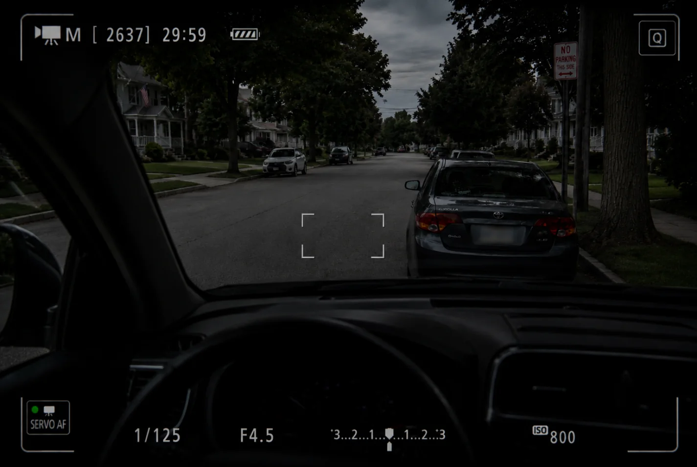 A surveillance view from inside a vehicle during a discreet neighborhood observation.